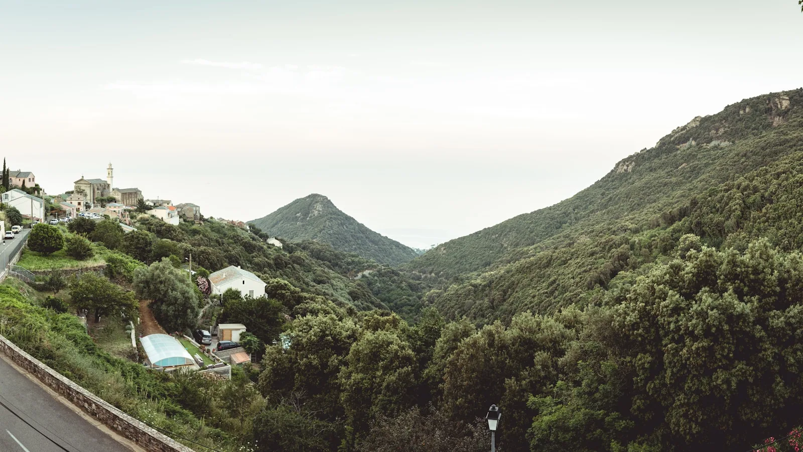 Route sinueuse de Corse avec une voiture de location sur une corniche dominant la mer