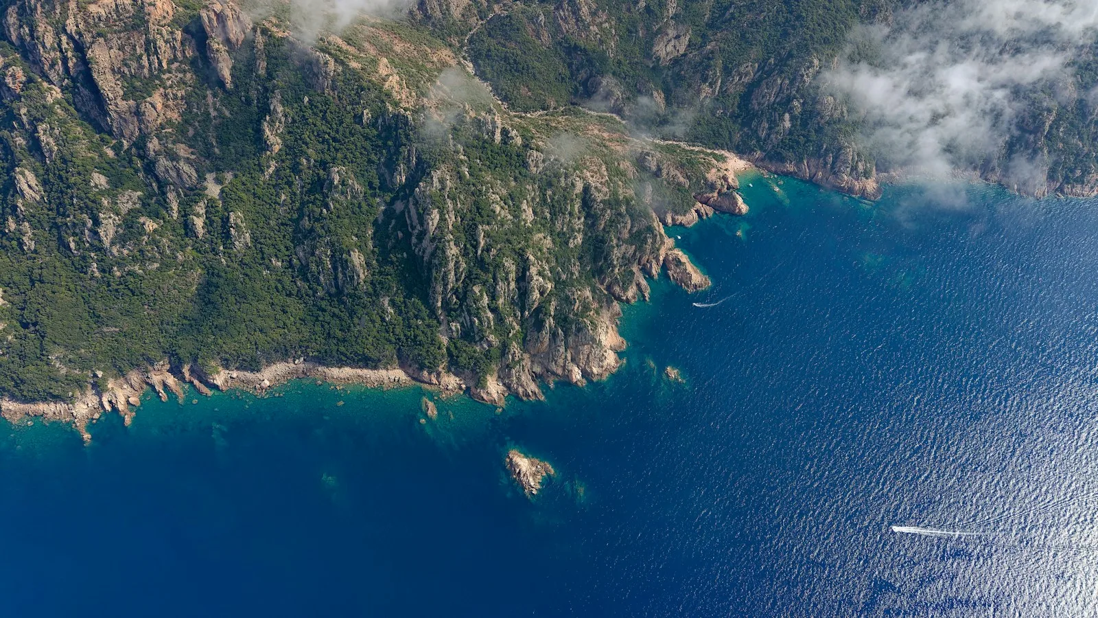 Bateau d'excursion longeant les falaises rouges de la réserve de Scandola en Corse